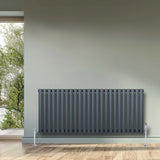 Oval single column radiator in anthracite grey, 600mm x 1440mm, featuring sleek vertical lines and chrome valves against a neutral wall