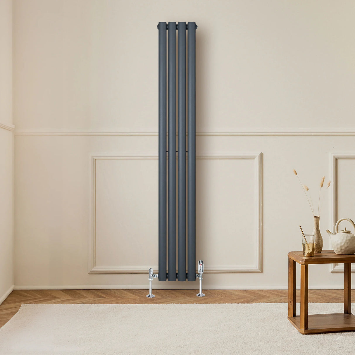 Anthracite grey oval single column radiator with sleek vertical design, mounted on a wall, complemented by stylish valves and a warm interior setting