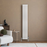 Sleek white oval single column radiator with valves, standing tall against a textured beige wall in a modern living space