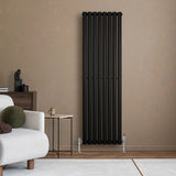 Sleek black oval single column radiator with vertical bars, positioned against a warm-toned wall, complemented by stylish valves