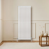 Sleek white oval single column radiator, 1600mm x 600mm, mounted on a wall, complemented by stylish valves and a cozy interior setting