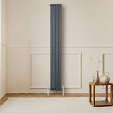 Sleek anthracite grey oval single column radiator with polished valves, positioned against a light-colored wall, enhancing modern decor
