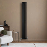 Sleek black oval single column radiator mounted on a textured beige wall, complemented by modern valves and minimalist decor