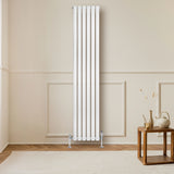 Sleek white oval single column radiator, 1800mm x 360mm, mounted on a wall, complemented by stylish valves and a cozy interior setting
