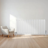 Flat single column radiator in white, 600mm x 1190mm, mounted on a wall beside a modern armchair in a bright room with wooden flooring