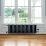 Traditional anthracite grey 4 column radiator with valves, featuring a sleek, vintage design against a bright window backdrop