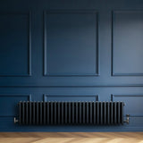 Traditional anthracite grey 4 column radiator with a sleek, ribbed design, mounted against a deep blue wall, enhancing modern decor