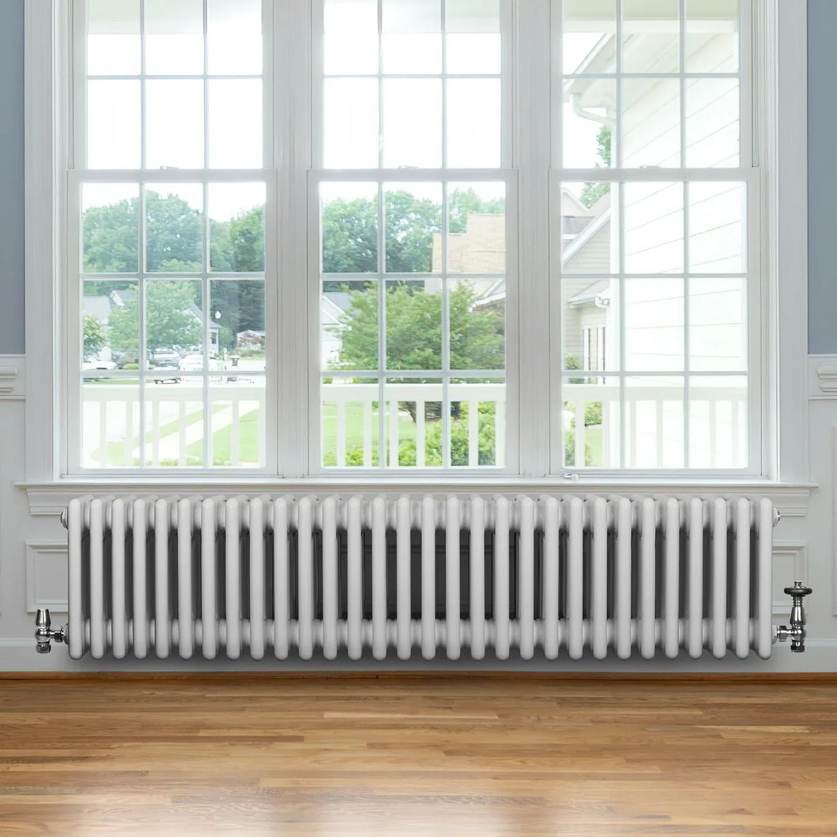 Traditional white 4 column radiator with valves, positioned under a large window, showcasing a sleek design and smooth finish