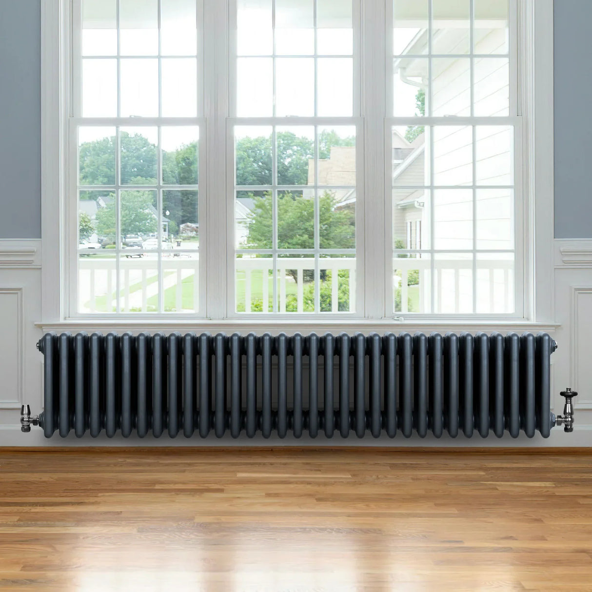 Anthracite grey traditional 4 column radiator with valves, featuring a sleek design and smooth finish, positioned under a large window