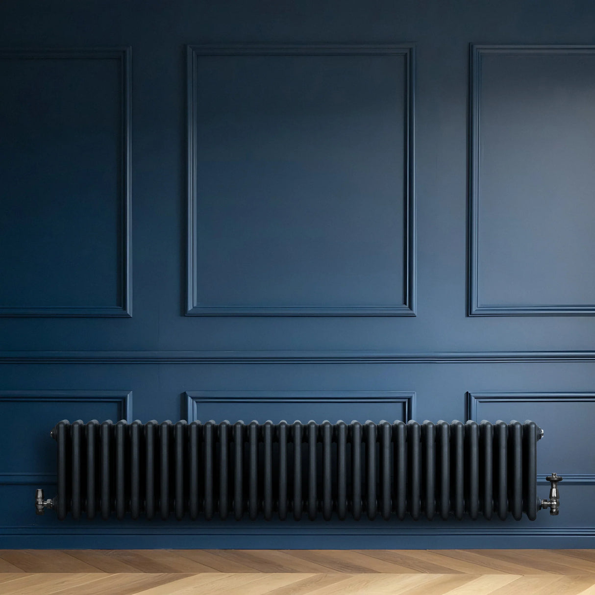 Traditional anthracite grey 4 column radiator with valves, featuring a sleek, elongated design against a deep blue wall backdrop