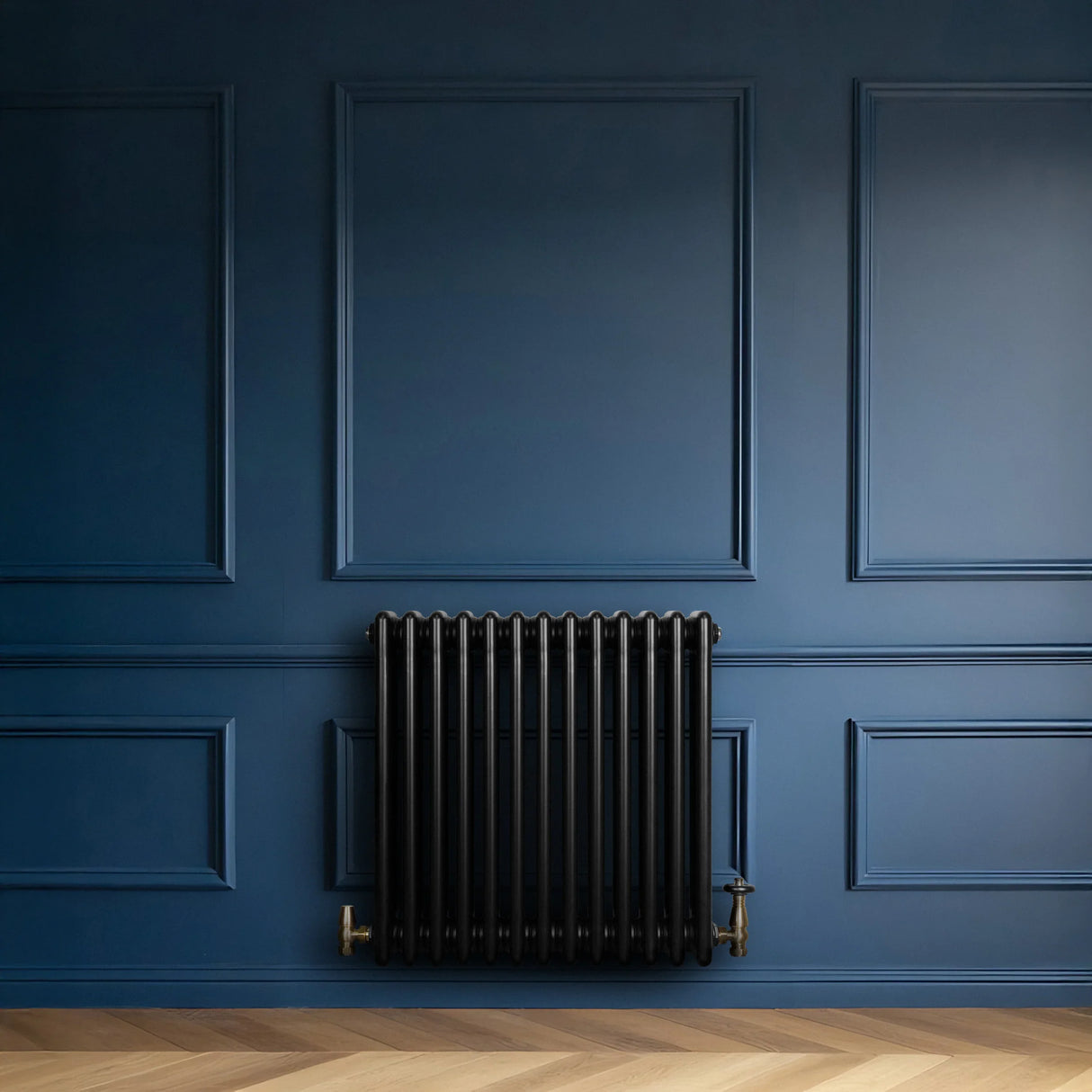 Traditional black 4 column radiator with brass valves, set against a deep blue wall and herringbone wood floor, showcasing elegant design