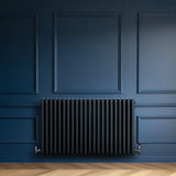 Traditional anthracite grey 4 column radiator with valves, featuring a sleek design against a deep blue wall and herringbone floor
