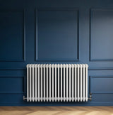 Traditional white 4 column radiator with smooth, glossy finish, mounted against a deep blue wall, enhancing modern decor