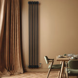 Traditional black 4 column radiator with valves, mounted on a warm beige wall, complementing a modern dining area with wooden furniture