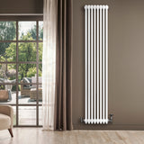 Tall, sleek white traditional 4 column radiator with valves, positioned beside a large window and soft curtains, enhancing modern decor