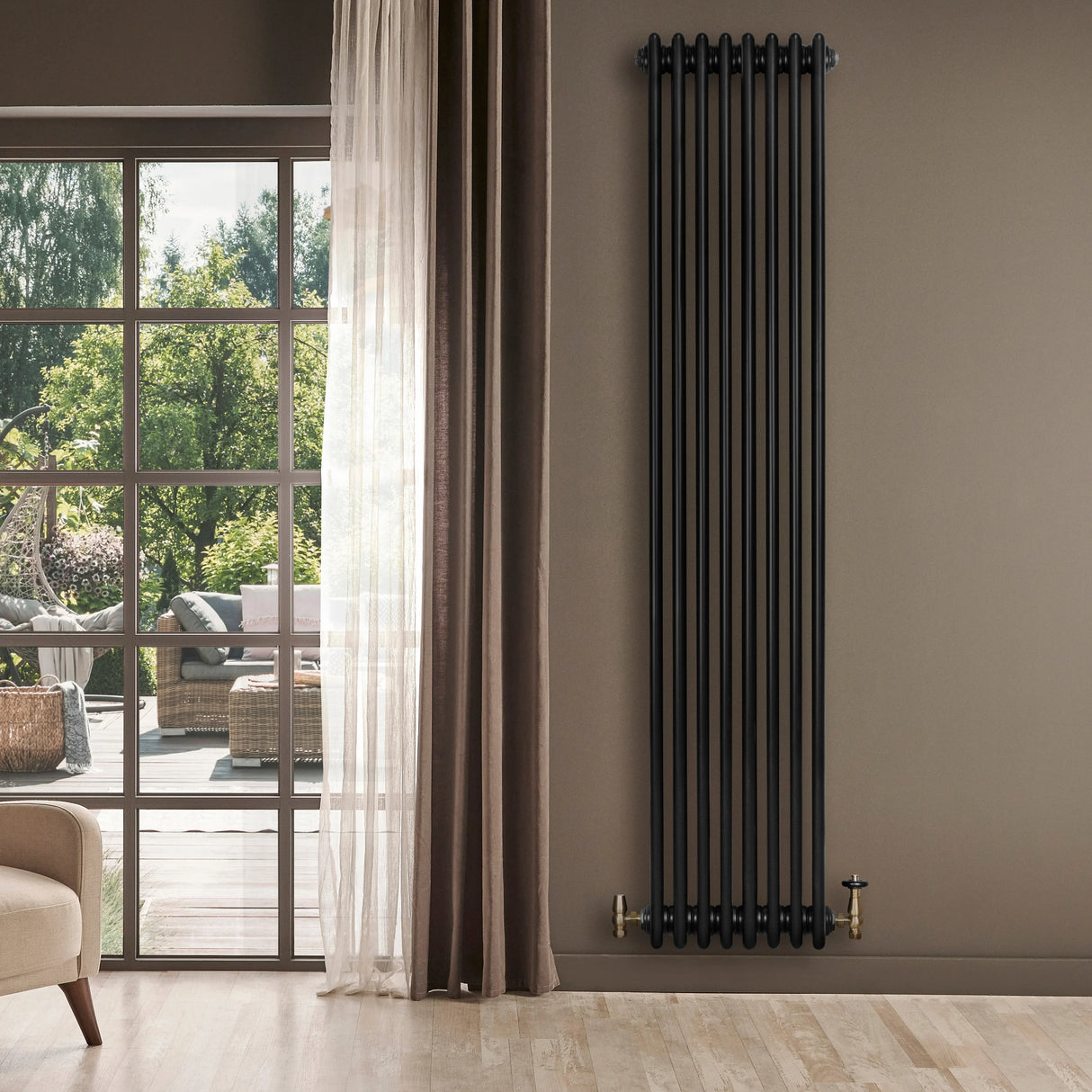 Traditional black 4 column radiator with brass valves, mounted on a wall beside large windows, enhancing a modern interior space