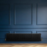 Traditional black 4 column radiator, 300 x 1370mm, mounted against a deep blue wall, showcasing a sleek, vintage design with elegant curves