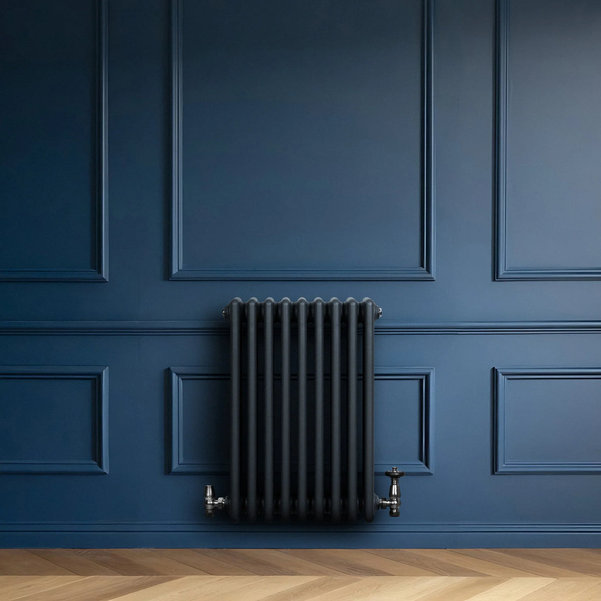 Traditional 4 column radiator in anthracite grey, featuring a sleek design against a deep blue wall and wooden floor