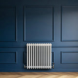 Traditional white 4 column radiator against a deep blue wall, featuring smooth, rounded edges and a sleek, modern design
