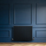 Traditional 4 column radiator in anthracite grey, featuring a sleek design with vertical tubes, mounted on a dark blue wall