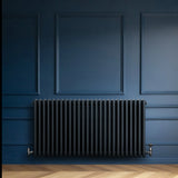 Traditional 4 column radiator in anthracite grey, featuring a sleek, ribbed design against a deep blue wall backdrop
