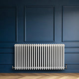 Traditional white 4 column radiator, 600 x 1190mm, mounted on a blue wall, featuring a sleek, glossy finish and vertical bars