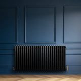 Traditional black 4 column radiator against a deep blue wall, featuring a sleek, glossy finish and elegant design, ideal for classic interiors