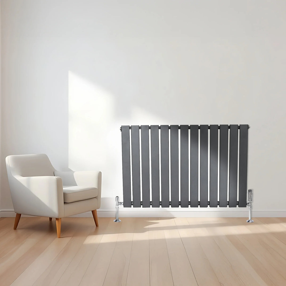 Flat single column radiator in anthracite grey, featuring sleek vertical lines, positioned beside a modern white armchair in a bright room