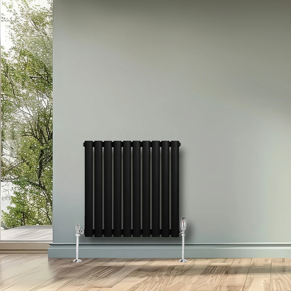 Sleek black oval single column radiator mounted on a light gray wall, complementing a modern interior with wooden flooring