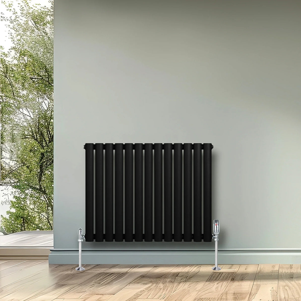 Sleek black oval single column radiator, 600 x 780mm, mounted on a light gray wall, complemented by modern chrome valves and a natural backdrop