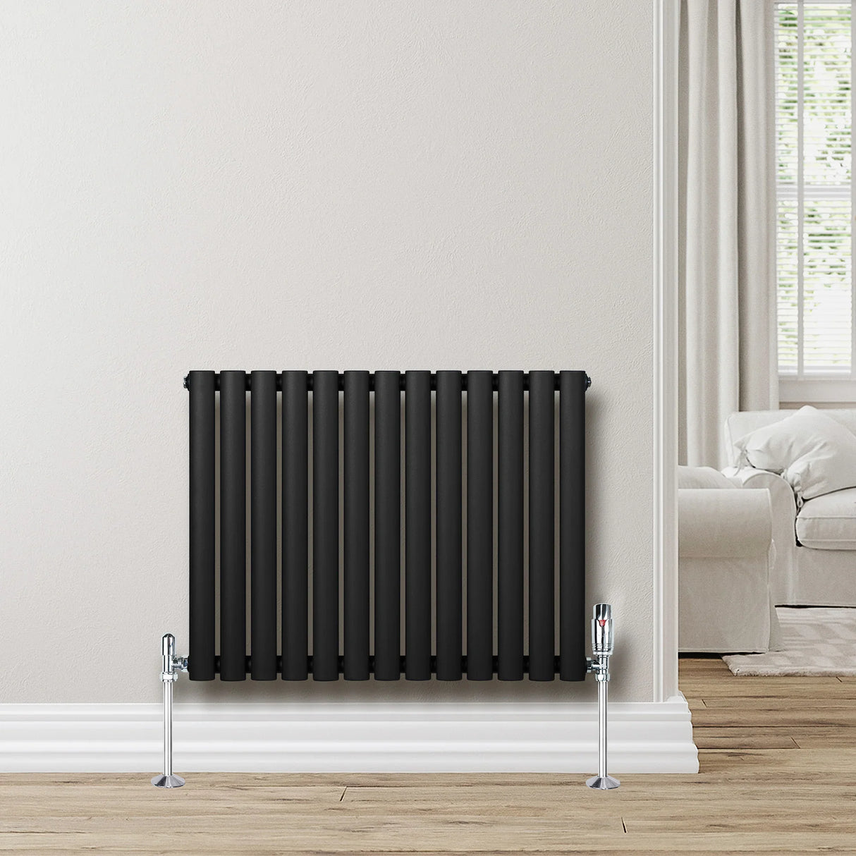 Sleek black oval single column radiator, 600 x 780mm, mounted on a light wall, with chrome valves and a modern living room backdrop