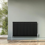 Sleek black oval single column radiator, 600 x 1020mm, mounted on a light wall, complementing a modern interior with wooden flooring