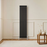 Sleek black oval single column radiator, 1600 x 360mm, mounted on a light wall, complementing a cozy living room setting