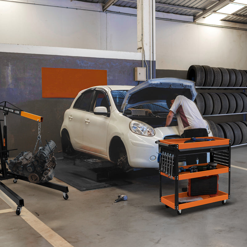 White car on a lift in a garage, with a mechanic working under the hood, surrounded by tires and a tool cart with tools