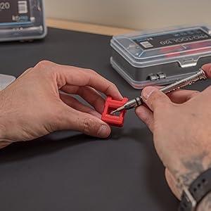 Precision screwdriver in hand, adjusting a red component, with ilabPRO 120 Piece set case visible in the background