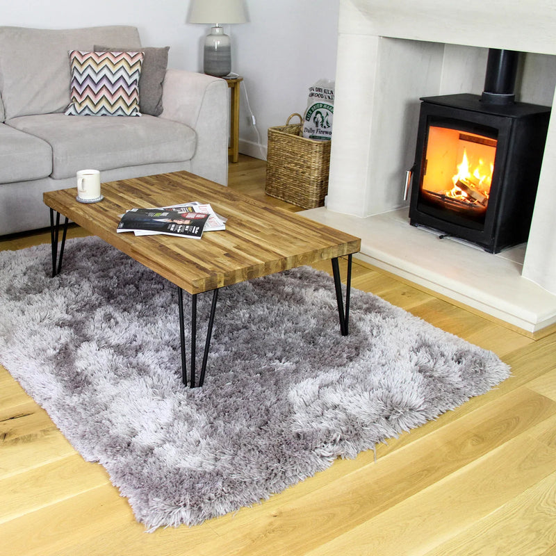 Black 12mm hairpin legs for furniture, showcasing a modern design with a sleek finish, complementing a rustic wooden table in a cozy living room setting