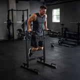 Athlete performing dips on sturdy black parallettes dip bars XL in a modern gym setting with weights in the background